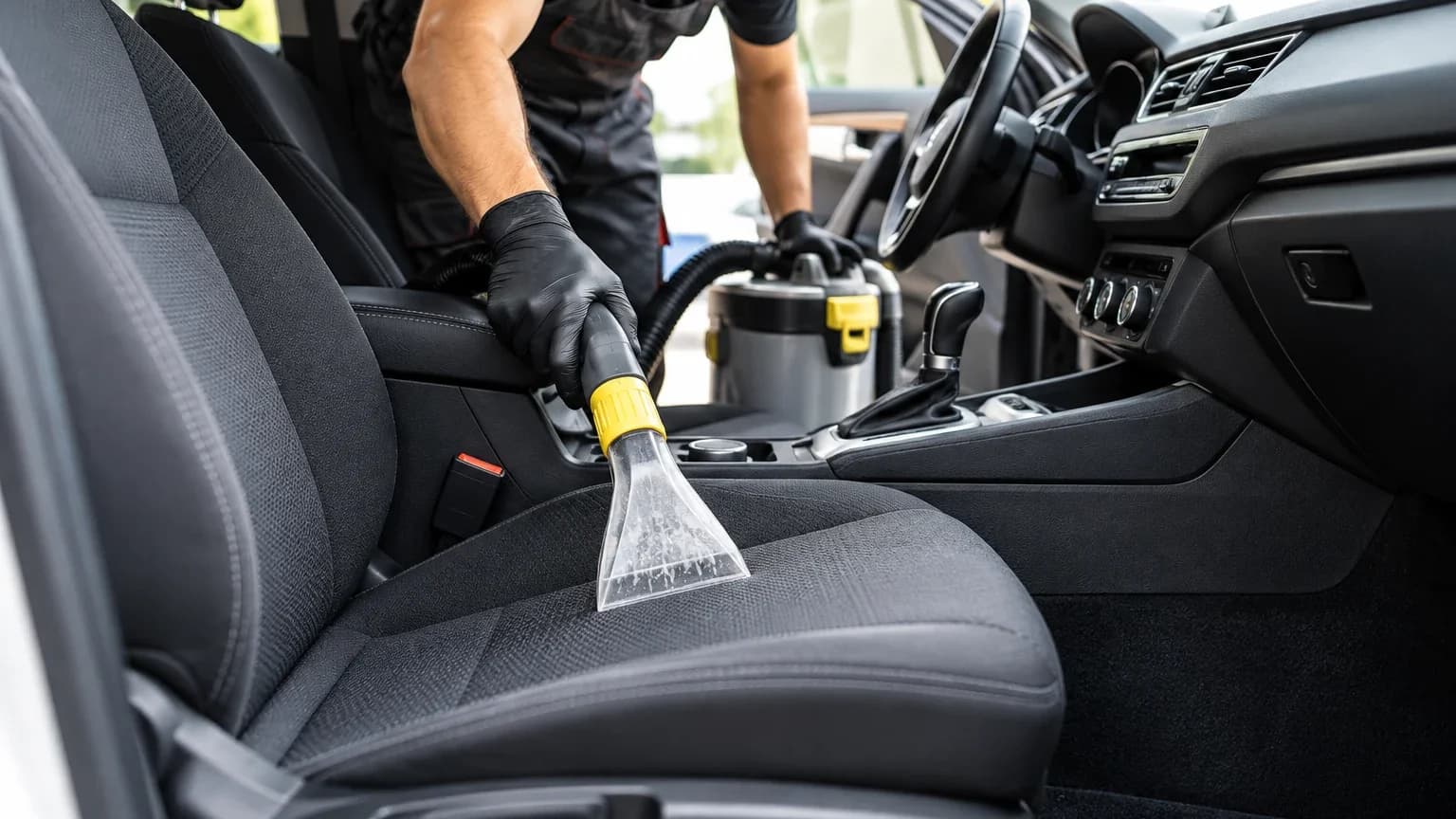 Un professionnel nettoie un siège de voiture avec une shampouineuse
